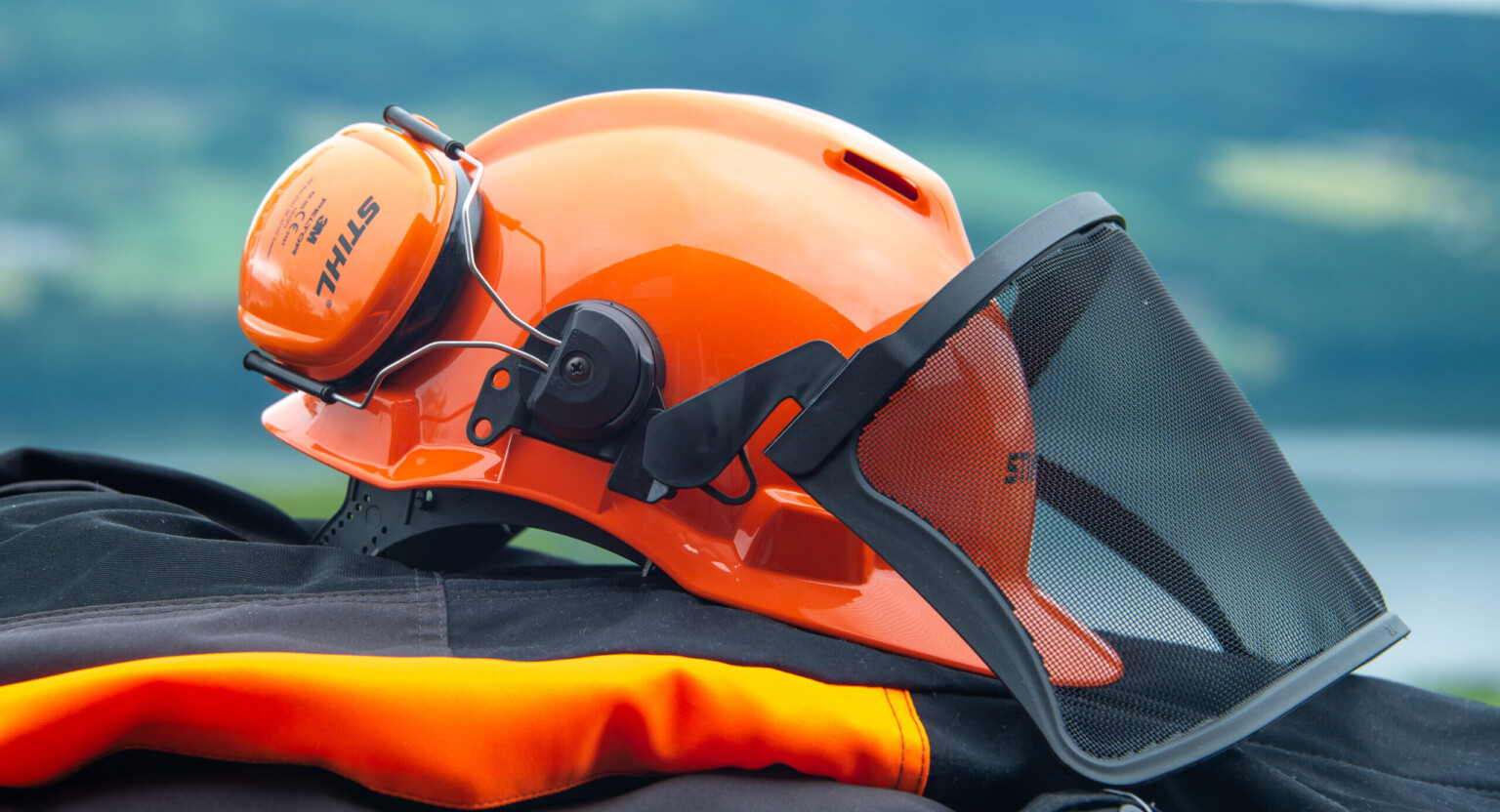 bilde av verneutstyr. hjelm med hørselværn og visir ligger oppå vernebukser.